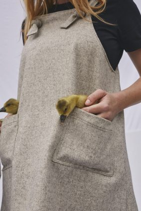 Tablier tissé beige avec deux poches dans lesquels résident deux canetons